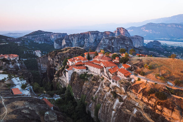 Вид с воздуха на монастыри Троицы и захватывающие фотографии долины и ландшафтного каньона Метеоры на закате, Каламбака, Греция, тени, извилистая дорога, мост, горы как колонны