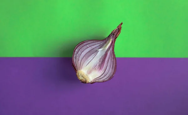 product purple delicious bitter onion in a cut lies in the middle of a bright green and purple background top view.for labels of store banners and advertisements of books with recipes flyers