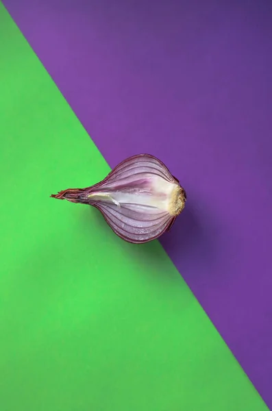 product purple delicious bitter onion in a cut lies in the middle of a bright green and purple background top view.for labels of store banners and advertisements of books with recipes flyers