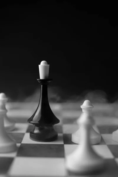 在比赛的棋盘上 有一块黑色皇后的棋子 周围是黑烟熏天的白爪 用来做横幅 比赛海报 — 图库照片
