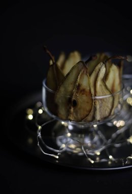 Karanlık bir arka planda ve siyah bir tepside şeffaf bir cam üzerinde kuru armutlar ve bir Noel ağacı dalı ve küçük bir karın üzerinde çelenkler duruyor. Ekran koruyucular, kartpostallar, etiketler, davetiyeler için