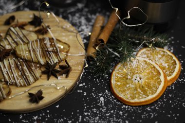 Kurumuş armutların noel süslemesi çikolatada, tarçın portakallarının ahşap standında ve karanlık bir arka planda Noel ağacı dallarında. kartpostallar için menü takvim işaretleri ve ayakta durur