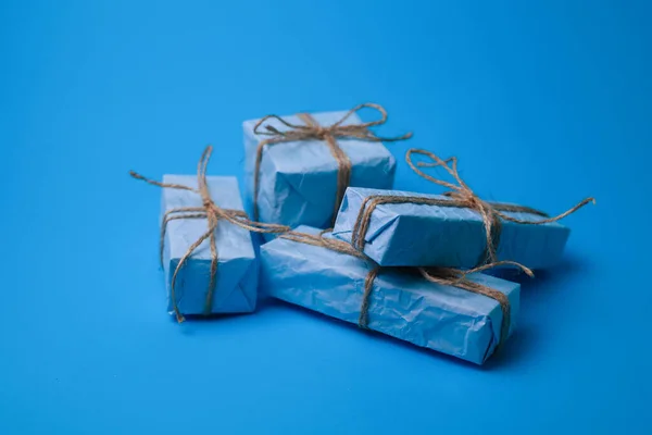 四个蓝色手工纸制的礼物 用绳子绑在蓝色背景上 带有或不带花环 适用于日历卡片屏幕保护程序邀请标签 — 图库照片