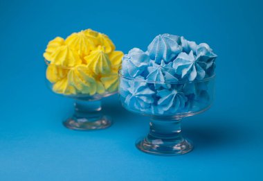 Sarı ve mavi tatlı pastalar parlak mavi bir zemin üzerinde şeffaf kadehlere dökülür. Yemek kitabı sıçrama ekranları için menü işaret etiketleri