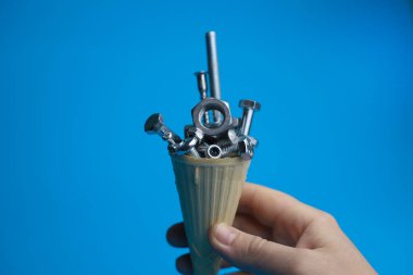 Fındıklar vidaları vidaları vidaları parlak mavi bir arka planda dondurma külahında vidaları ve bir erkeğin elinde tutuluyor. Etiketler, işaretler, el ilanları, depolama işaretleri vs. için.