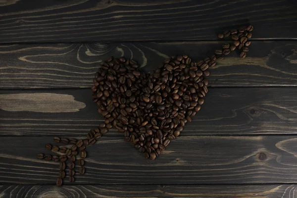 fragrant rich coffee beans of different varieties on a dark wooden surface are laid out in the form of a cat. for banners, flyers, splash screens, menu labels