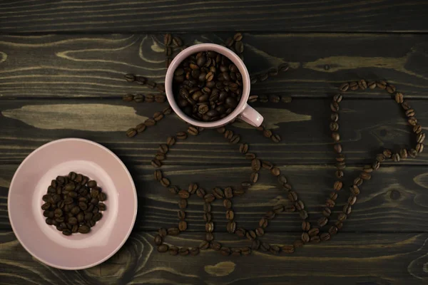 a cat with a cup of coffee instead of a muzzle and a saucer with coffee is laid out of fragrant coffee beans on a wooden background