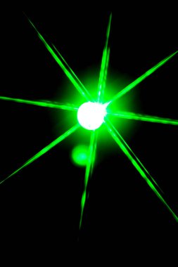 blurred bokeh in the shape of a star of bright psychedelic neon colors of light green orange yellow and red on a dark background.