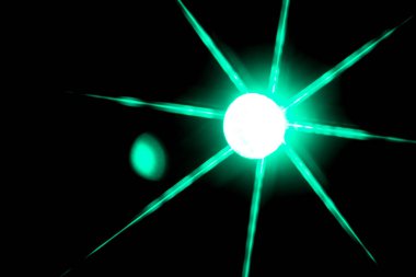 blurred bokeh in the shape of a star of bright psychedelic neon colors of light green orange yellow and red on a dark background.