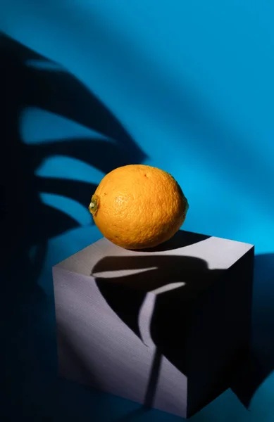 yellow sour whole lemons on a square stand on a bright blue background cast a deep shadow. for postcards, napkins, coasters, screensavers, fruit and vegetable stores