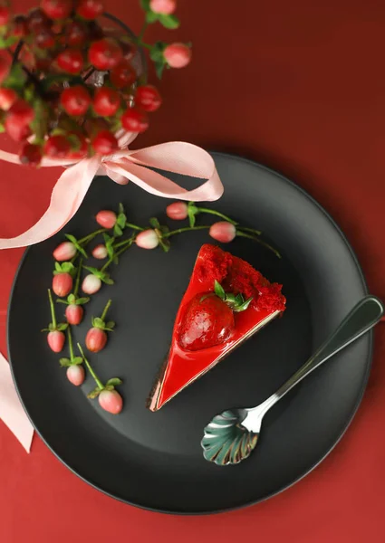 一片美味的甜而美丽的明亮的蛋糕 上面有草莓在一个黑色的厨房盘和一个红色的背景 周围装饰着粉红色的浆果 — 图库照片