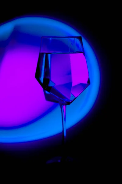 透明玻璃杯 用霓虹灯浸透的彩虹色的水 — 图库照片