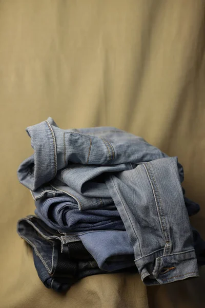 second hand clothes are stacked on top of each other, denim in different shades on a fabric background and in a box. reuse clothes without harming the planet