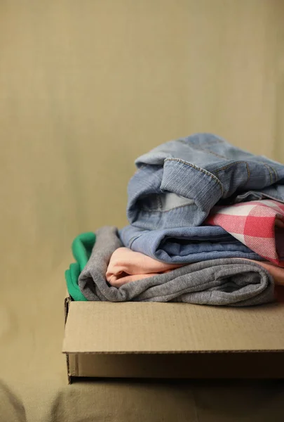 second-hand clothes are stacked on top of each other blue jeans knitted sweater and colored green and pink pants on a fabric background and in a box