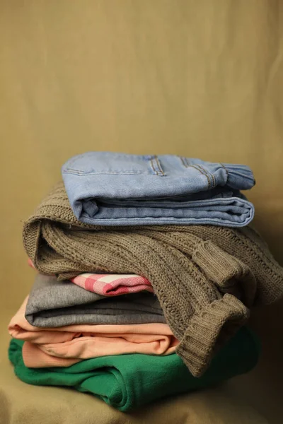 second-hand clothes are stacked on top of each other blue jeans knitted sweater and colored green and pink pants on a fabric background and in a box