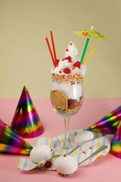 イースターパーティー 透明なワイングラスに3つの卵の横にある色の違うイースターケーキにラズベリークッキーとホワイトコットンキャンディーを振りかける明るいカクテル — ストック写真