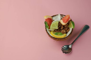 Hindistan cevizli gevrek, limonlu dilimlenmiş çikolata taneleri ve pembe arka planda hindistan cevizi kabuklu greyfurt.