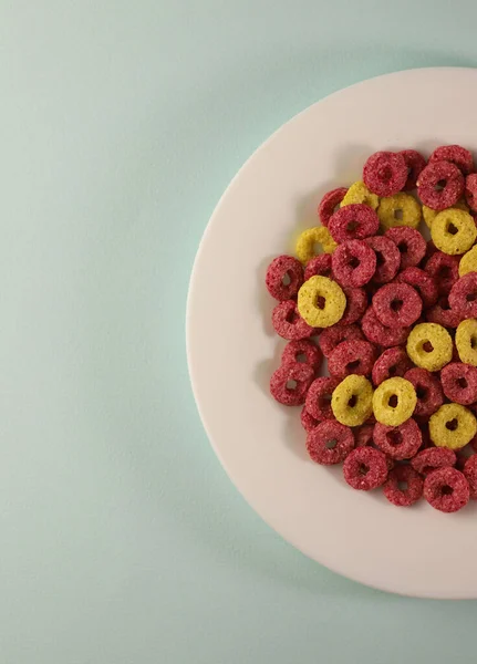 異なる色のリングでおいしい甘い健康的な朝食コーンフレーク異なる背景に黄色とピンク 広告紹介 ラベル メニュー バナーなどのために — ストック写真