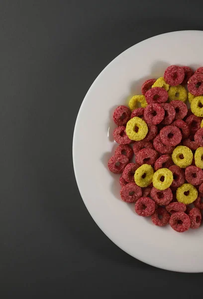 異なる色のリングでおいしい甘い健康的な朝食コーンフレーク異なる背景に黄色とピンク 広告紹介 ラベル メニュー バナーなどのために — ストック写真