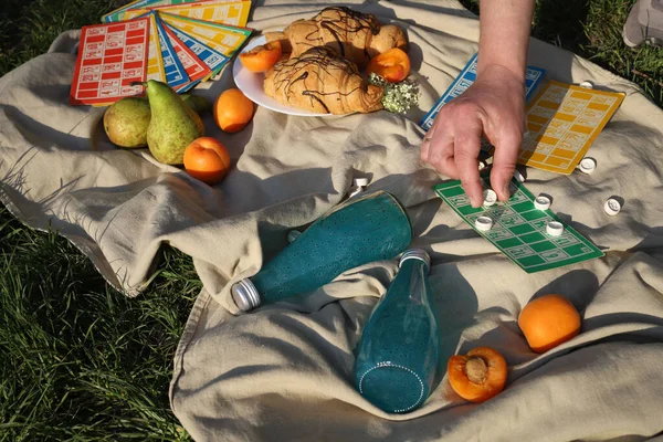 board logic game for family and friends picnic bingo, the game is placed on a picnic blanket in nature on a sunny summer day with croissants, apricot slices and drinks. for screensavers, postcards, advertising