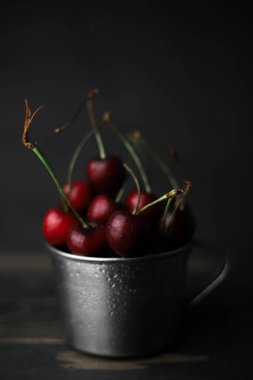 Beyaz dumanlı siyah bir arka planda siyah bir camda kırmızı-bordo renkli tatlı kirazlar. Kartpostallar, broşürler, afişler, etiketler, ekran koruyucular ve daha fazlası için