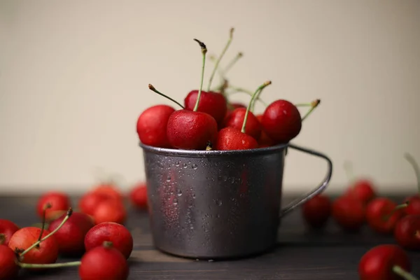 Stock image ripe summer sweet red cherry with water drops in a tin cup on a wooden and light background. for leaflets screensavers postcards advertising and more