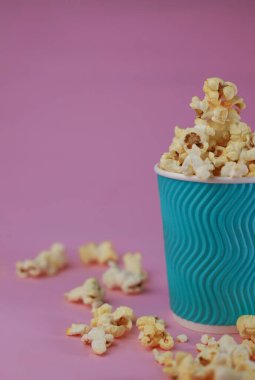 hazır tatlı ve tuzlu lezzetli patlamış mısır açık mavi bir zemin üzerinde bir bardak parlak aquamarine renginde. Kartpostallar, ekran koruyucular, el ilanları, tanıtım menüleri vs..