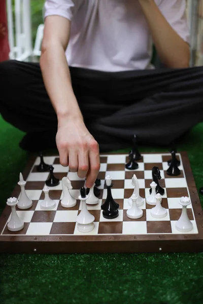 逻辑策略棋盘国际象棋为家人和朋友 在照片中 这个家伙正坐在一个绿色的草坪上学习和下棋 — 图库照片