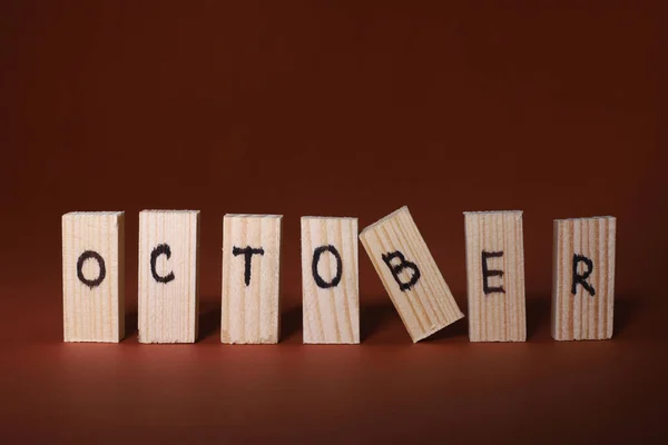 在褐色的背景上 木制的长方形轻质字母 上面刻着十月的字样 — 图库照片