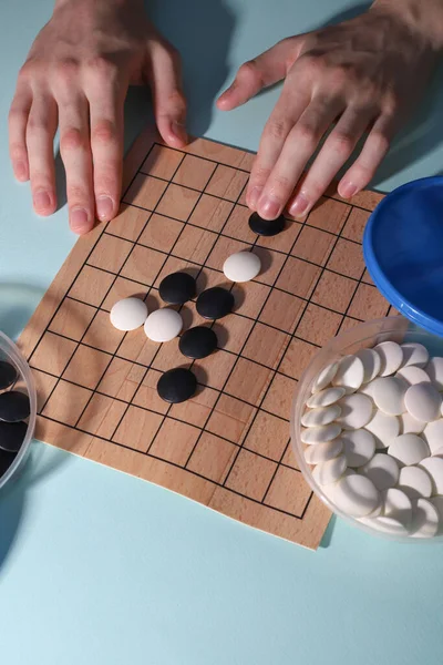 logical strategy game Go. black and white chips on the playing field. player's hands on the playing field