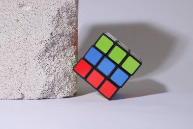 Hafif arkaplanda desenli beyaz bir tuğlanın yanında mekanik bulmaca kübü
