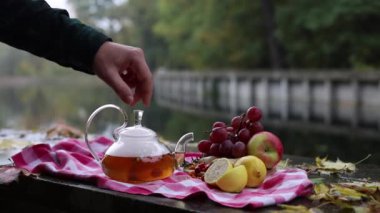 video. Şeffaf bir çaydanlıkta, deniz dikeninden, zencefilden, biberiyeden, limondan yapılmış sağlıklı bir sıcak çay. Erkek eli su ısıtıcısının kapağını kaldırır ve buhar çıkar.