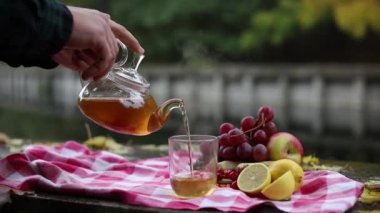 video. Sonbahar. Şeffaf bir çaydanlıktan, erkeklerin elleri şeffaf bir fincana deniz dikeninden, zencefilden, biberiyeden, limondan sağlıklı sıcak çay döker..