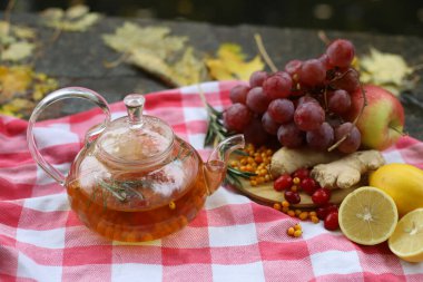 Doğal soğuk algınlığı ilaçları. Doğal malzemelerden gelen tıbbi çay limon, zencefil, deniz dikenleri, sonbahar doğasında şeffaf bir çaydanlıkta biberiye.