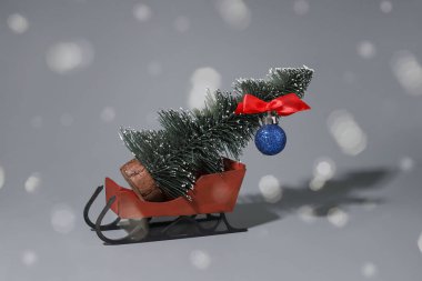 Yeni yıl konsepti. Noel Baba 'nın gri arka planda bordo renginde kızağı. İçlerinde bir Noel ağacı var. bokeh