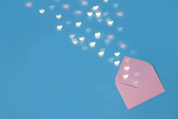 there is a pink envelope on a blue background and hearts are pouring out of the envelope