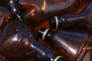 Plastik. Kahverengi plastik şişeler yan yana yatar. Gezegen kirliliği