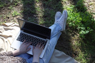 Doğada çalışmak ve çalışmak. Beyaz dizüstü bilgisayar bir kızın ellerinde.