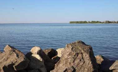 Göldeki panorama. Kayalık kıyı ve ufukta deniz manzarası
