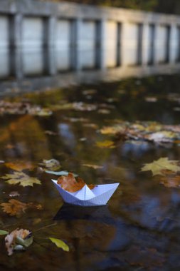 Suda, nehirde ya da gölde kağıt tekne. Teknede bir sonbahar yaprağı var. sonbahar