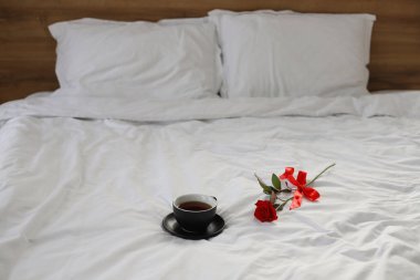 Kırmızı bir yay ve siyah bir fincan kahve ya da beyaz bir yatakta çay..