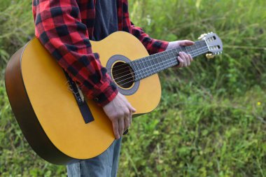 Kırmızı gömlekli ve kot pantolonlu genç bir adam yeşil dağlarda ve doğada tek başına dolaşır..