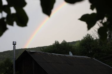 Yağmurdan sonra bir evin çatısında gökkuşağı.