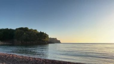 Uzak bir şatosu, önünde bir su kütlesi ve üzerinde kabarık bulutlar olan güzel bir gökyüzü olan sakin bir manzara.