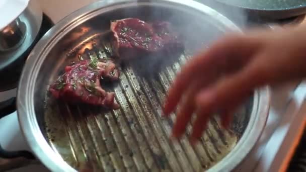 人間は 材料として動物性脂肪を使用して ガスストーブの上にグリルで豚肉を調理しています この料理は 香ばしい料理を作成するために動物性食品を粉砕することを含みます — ストック動画
