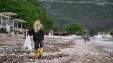 Genç bir kız sahilde çöp topluyor, suyu ve bitkileri korumaya yardım ediyor. İnsanları doğayı temiz ve güzel tutmaya teşvik etmek.
