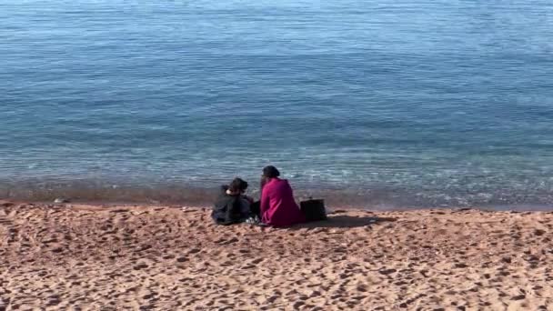 Два Человека Отдыхают Берегу Спокойного Водоема Наслаждаясь Спокойным Ландшафтом Неторопливым — стоковое видео