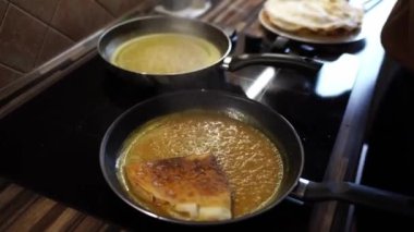 Aşçı krepleri kızartma tavasına kıvrılmış halde haşlanmış tatlı sosla birlikte yığıyor. Yüksek kalite 4k görüntü