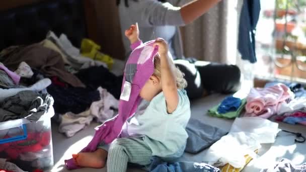 Mała Dziewczynka Kładzie Pranie Głowie Obok Matki Składającej Pranie Łóżku — Wideo stockowe