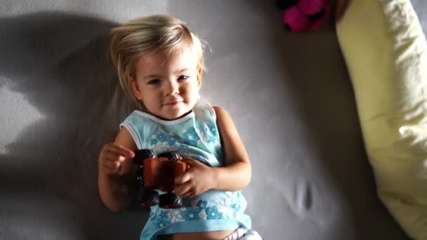 Маленька Дівчинка Носить Іграшковий Автомобіль Животі Лежачи Ліжку Високоякісні Кадри — стокове відео